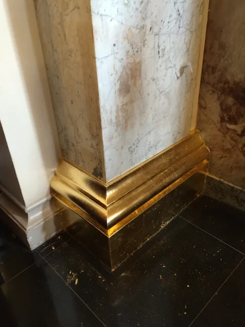 Gilded architectural base beside the faux-marble finish